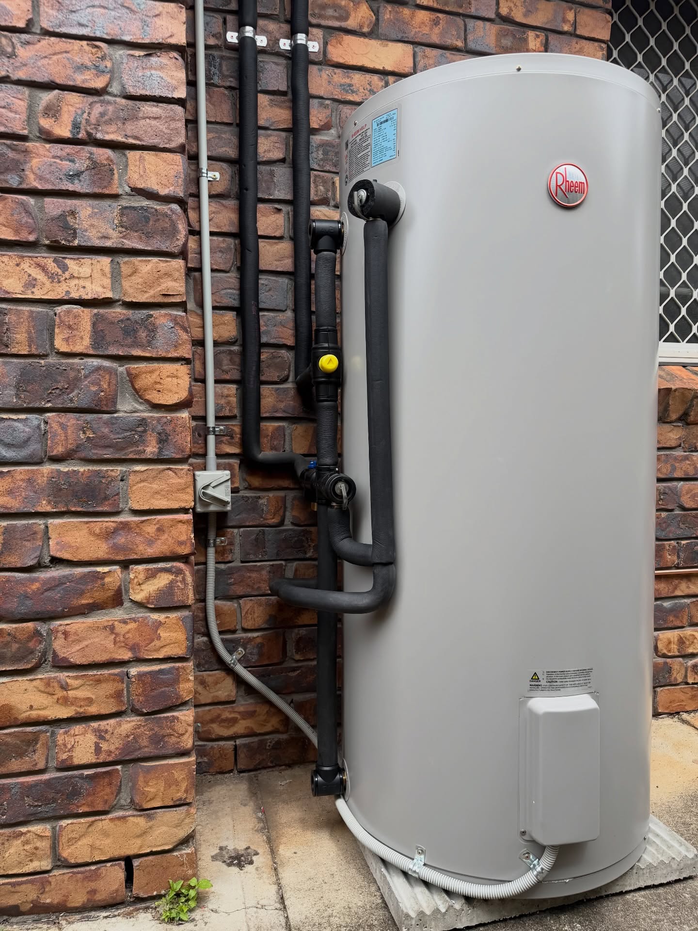 Heat pump hot water system installed on the side of a Brisbane home